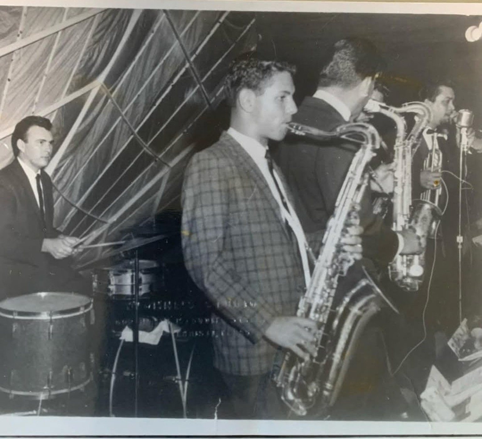 Black and white photo of Tejano musicians performing with saxophones and drums